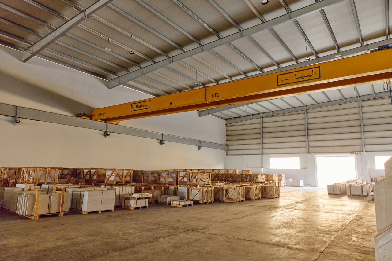 Interior view with rows of timber crates and slabs under a gantry crane